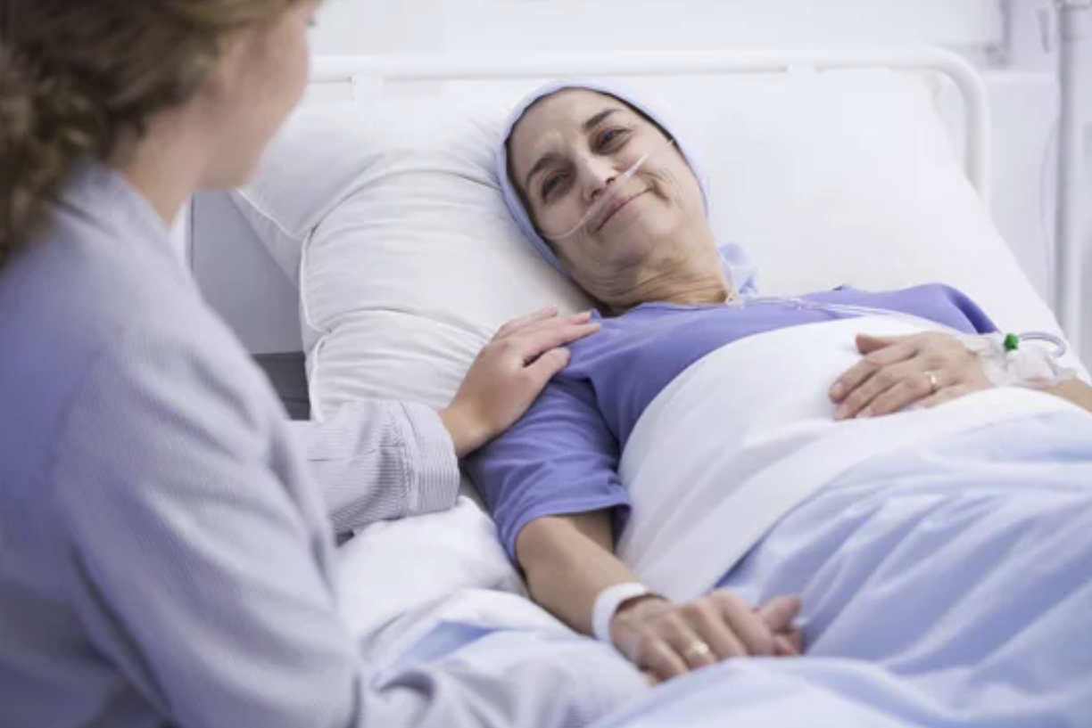 A compassionate healthcare worker comforts a smiling patient in a hospital bed, offering reassurance and support.