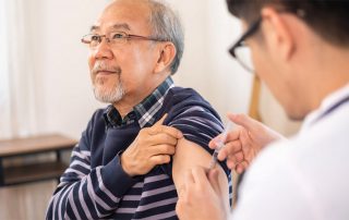 A nurse gives a vaccination to an elderly patient.