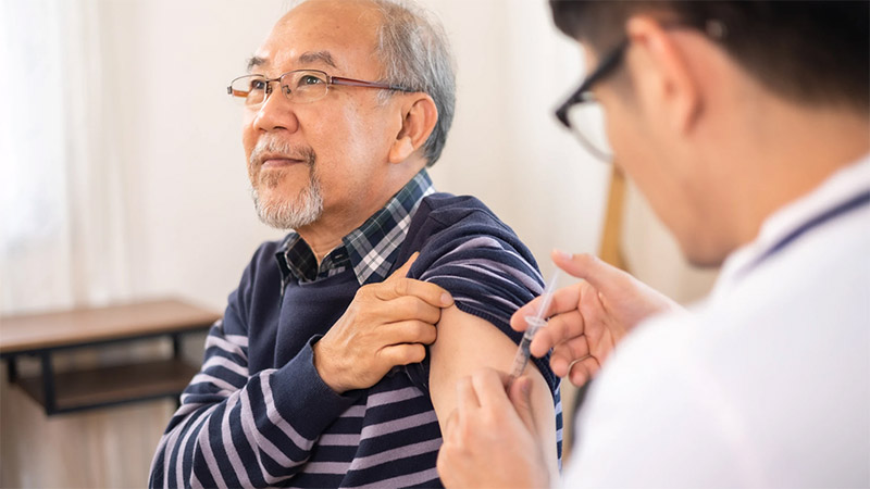 A nurse gives a vaccination to an elderly patient.